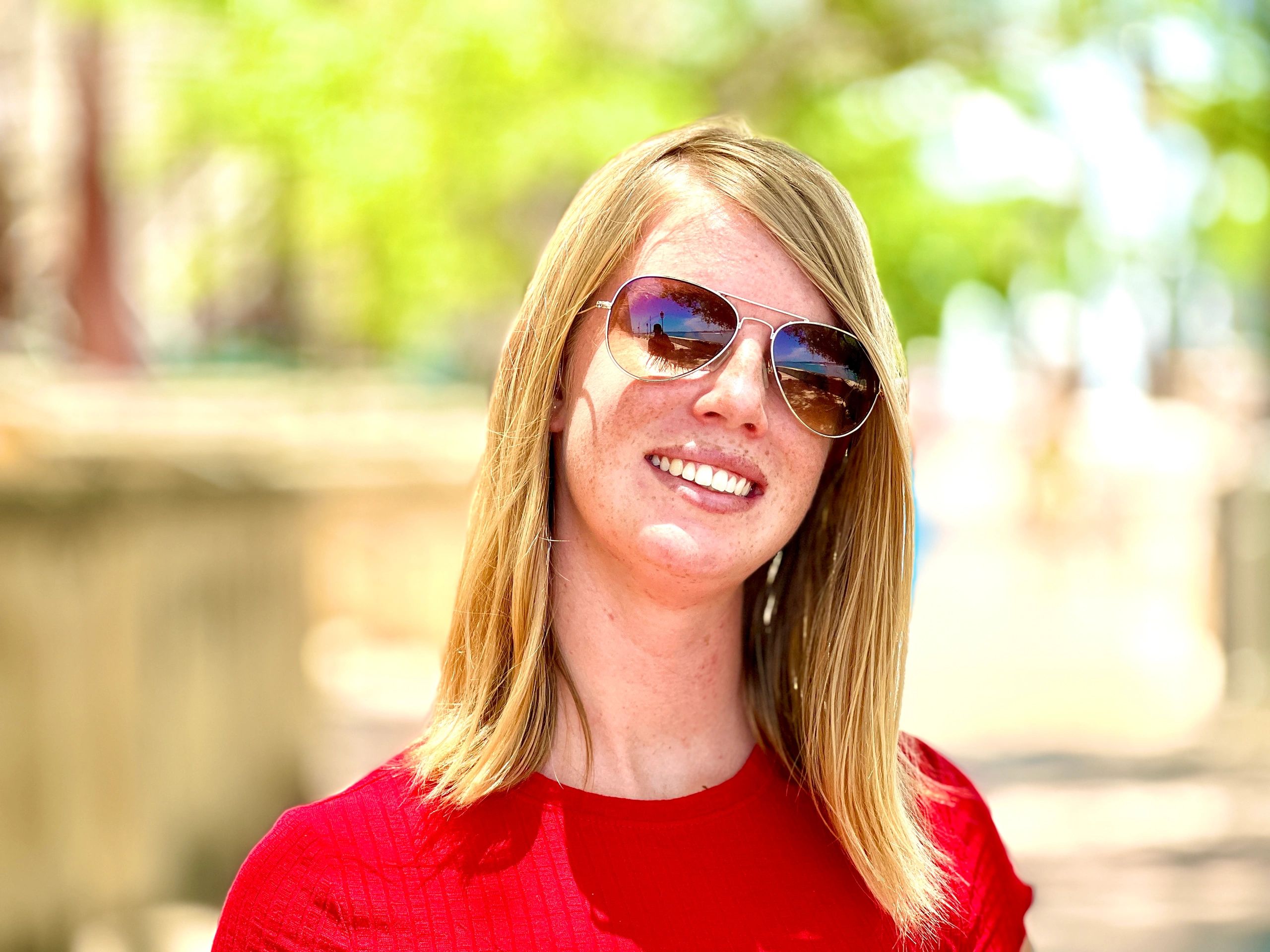 Landon smiling outdoors in sunglasses and a red top.